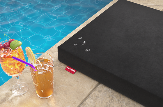 Photo d'un coussin d'assise posé près d'une piscine avec un cocktail.