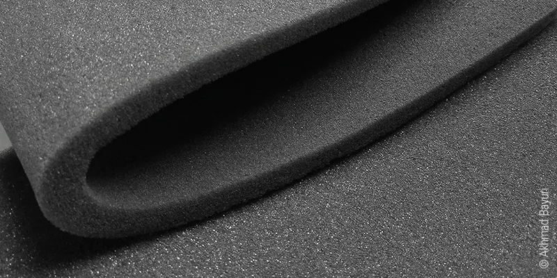 Gros plan sur une mousse polyuréthane foncée.