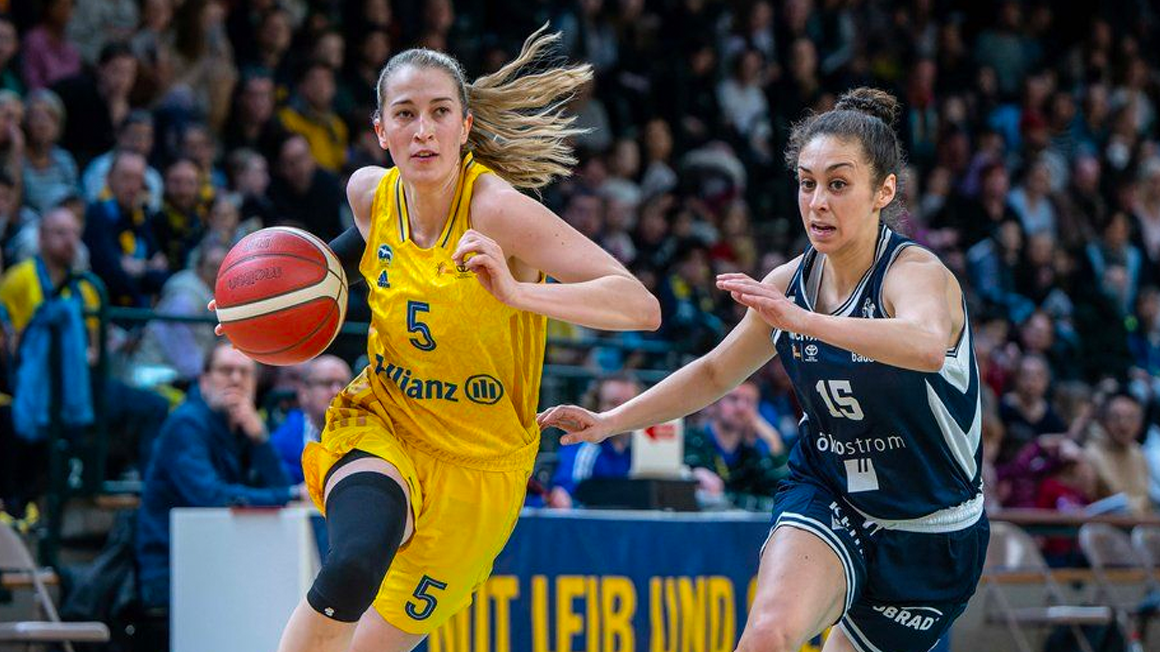 Foto: Zwei Personen in Trikots rennen zu einem fliegenden Ball.