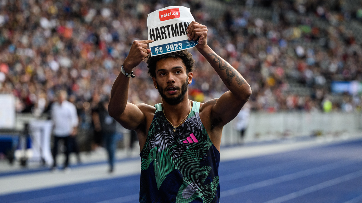 beim letzten etwas Kuddelmuddel:  Foto: Ein Läufer auf einer Tartanbahn hält mit beiden Armen ein Schild mit Namen und bett1-Logo über seinen Kopf.