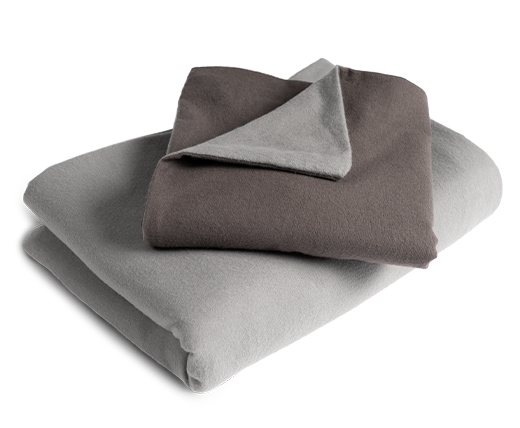 Le linge de lit BODYGUARD® en flanelle plié : la housse de couette est pliée avec la face grise vers l'extérieur, la taie d'oreiller avec la face couleur anthracite.