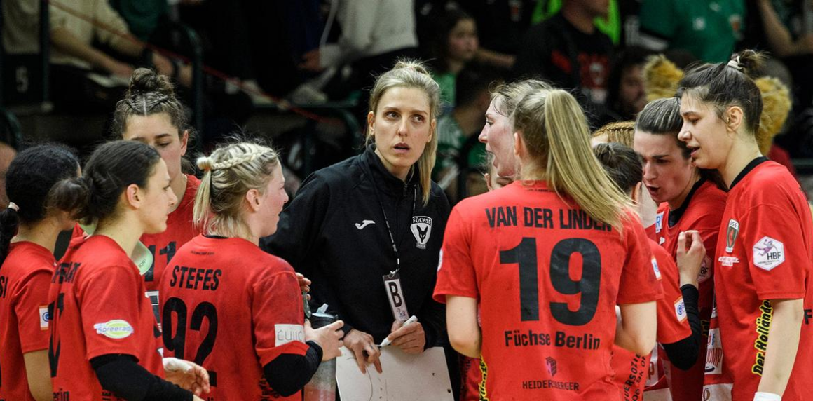 Foto: Die Spielerinnen der Spreefüxxestehen mit teild geöffneten Mündern vor ihrer Trainerin am Spielfeldrand.