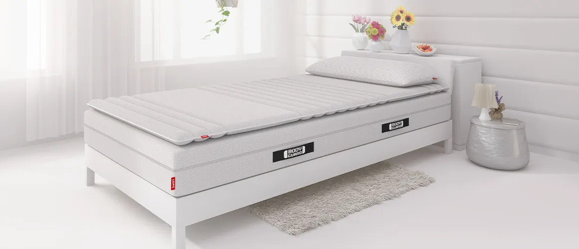 Une chambre claire avec un matelas sur lequel il y a un surmatelas posé.