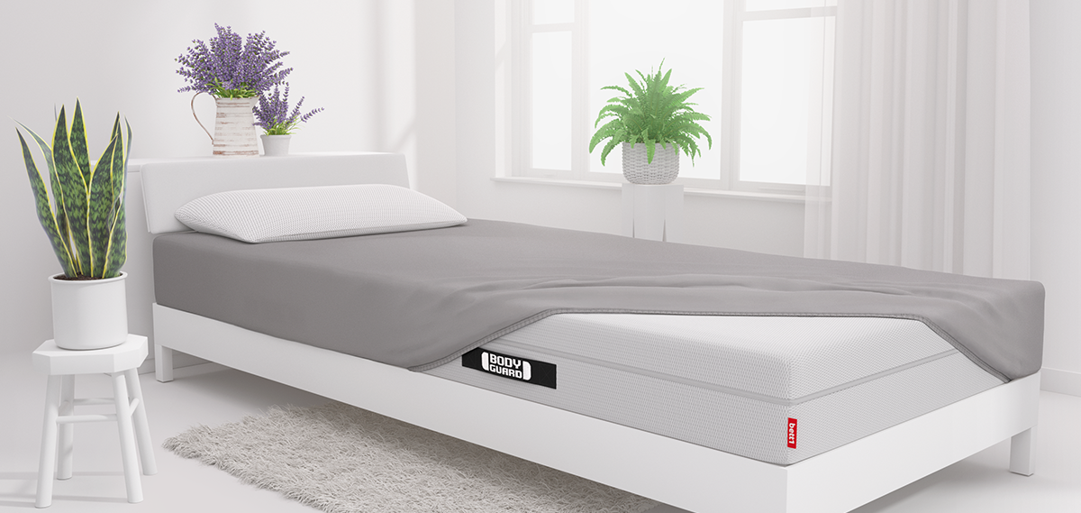 Eine Matratze zur Hälfte mit einem Spannbettlaken bezogen in einem hellen Schlafzimmer