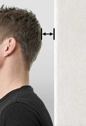 Homme vu de profil debout devant un mur, avec une double flèche indiquant l’espace entre l’arrière de sa tête et le mur.