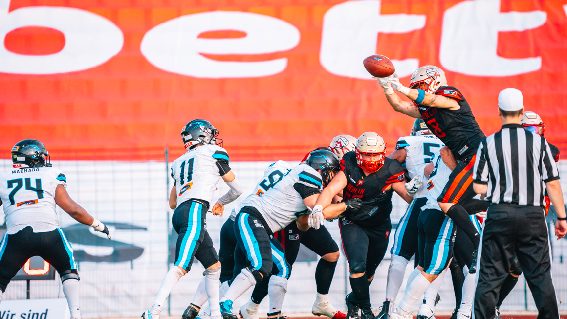 Foto: Mehrere Personen in Football-Montur vor einem rot-weißen bett1-Banner.