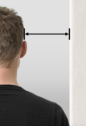 Homme vu de dos face à un mur, avec une double flèche indiquant la distance entre sa tête et le mur.