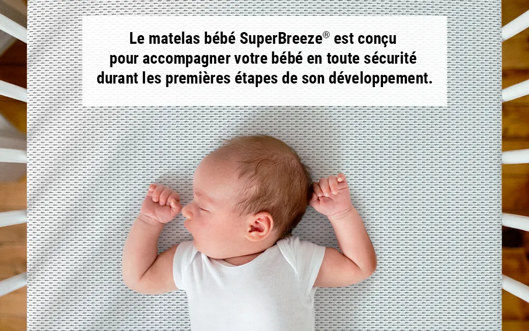 Gros plan sur un bébé debout dans un lit à barreaux sur un matelas enfant BODYGUARD