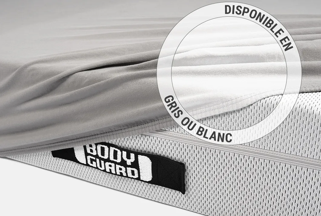 La moitié du matelas BODYGUARD® est recouverte du drap-housse en jersey gris. Texte : Disponible en gris ou en blanc