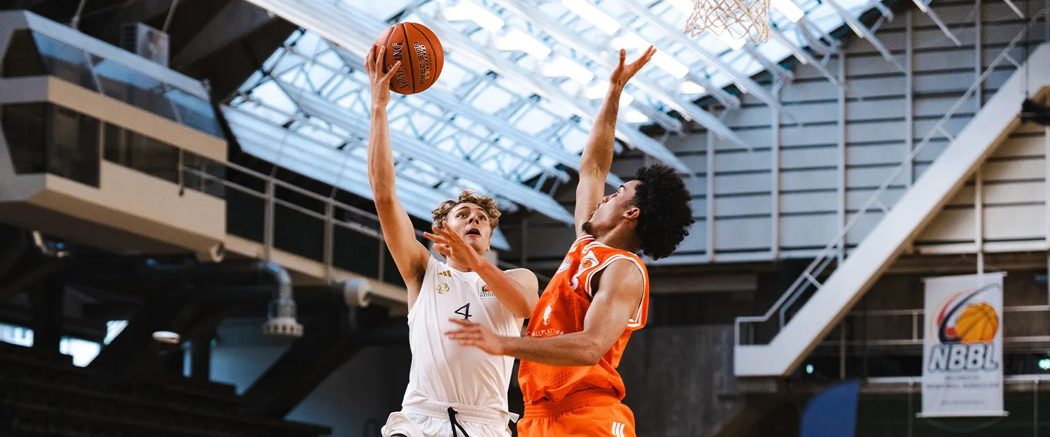 Foto: Ein Spieler der Berlin Dreams springend und mit Ball in der Hand im Duell gegen einen gegnerischen Spieler.