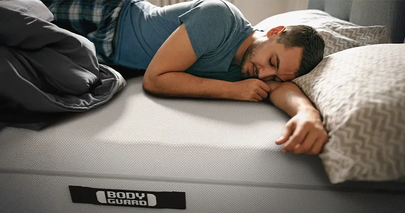 Homme endormi paisiblement sur un matelas BODYGUARD® sans drap-housse.