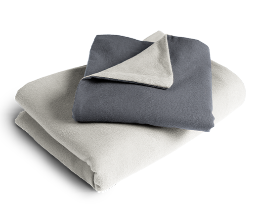 Le linge de lit BODYGUARD® en flanelle plié : la housse de couette est pliée avec la face grise vers l'extérieur, la taie d'oreiller avec la face couleur anthracite.