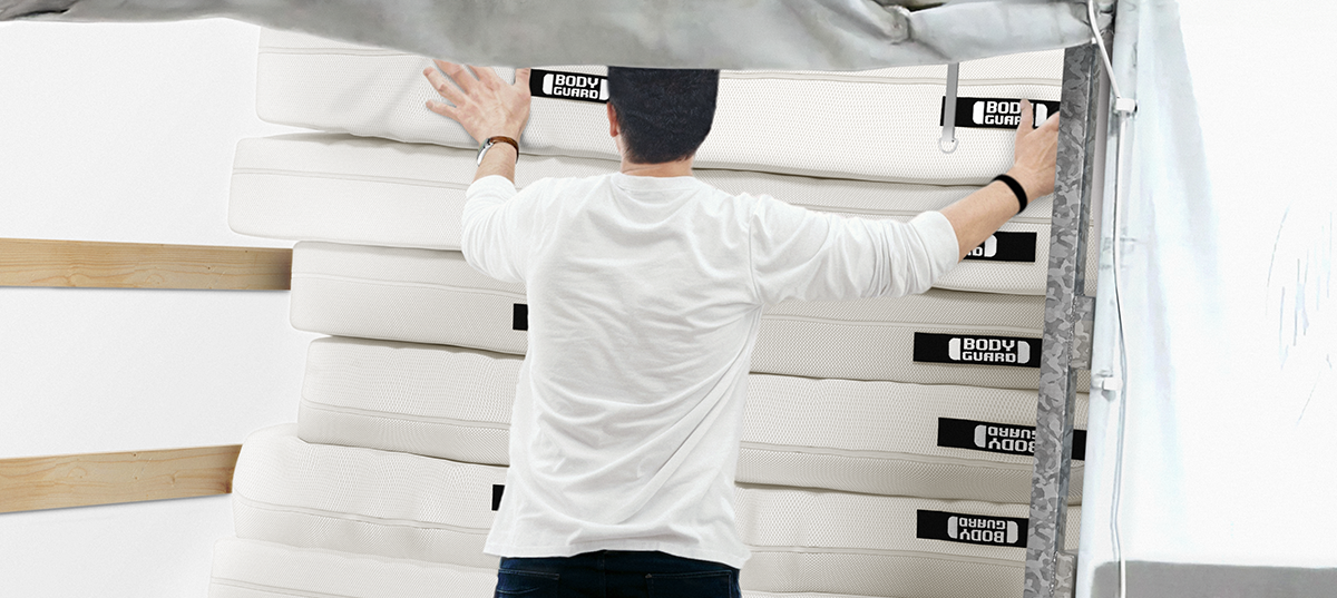 Un homme dispose des matelas Bodyguard les uns sur les autre