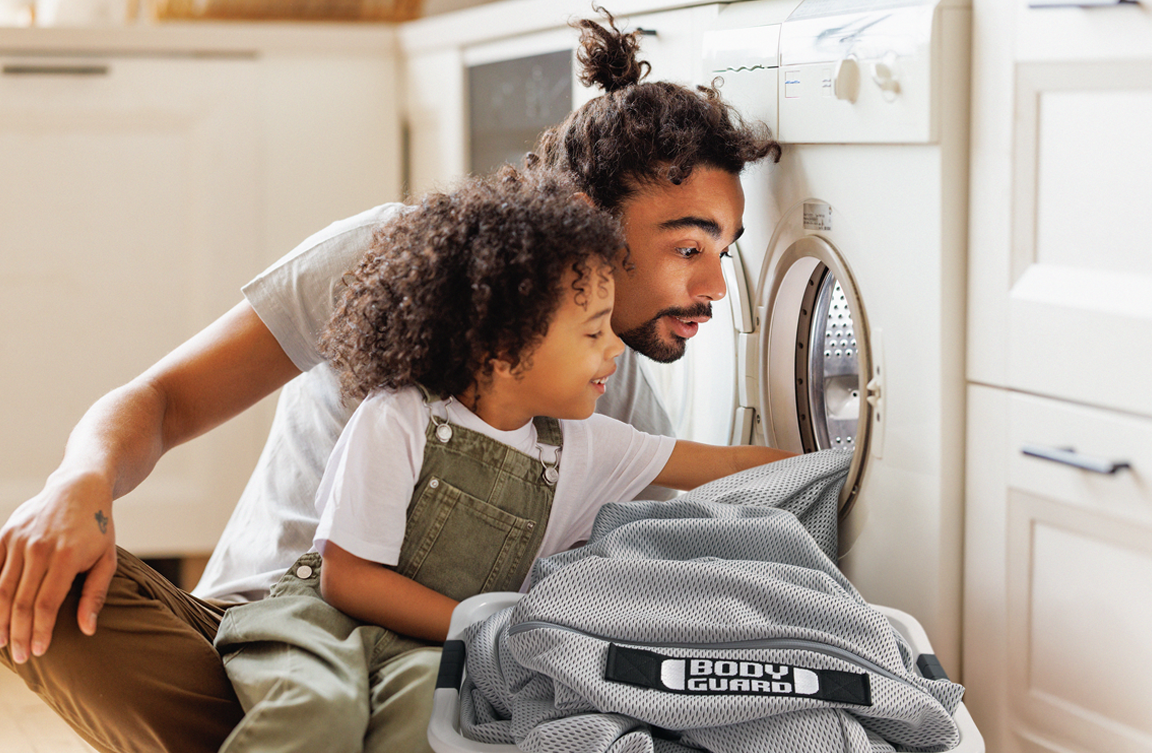 Photo : un adulte et un enfant placent la housse fonctionnelle HyBreeze dans une machine à laver.