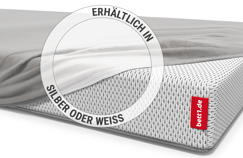 Ein Baby liegt in einem Kinderbett auf einer Babymatratze, die mit dem Kinder-Spannbettlaken in Silber bezogen ist.