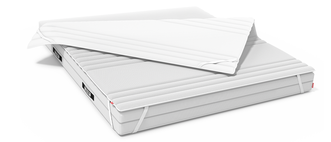 Surmatelas BODYGUARD® partiellement replié, fixé sur un matelas BODYGUARD® à l’aide de sangles élastiques.