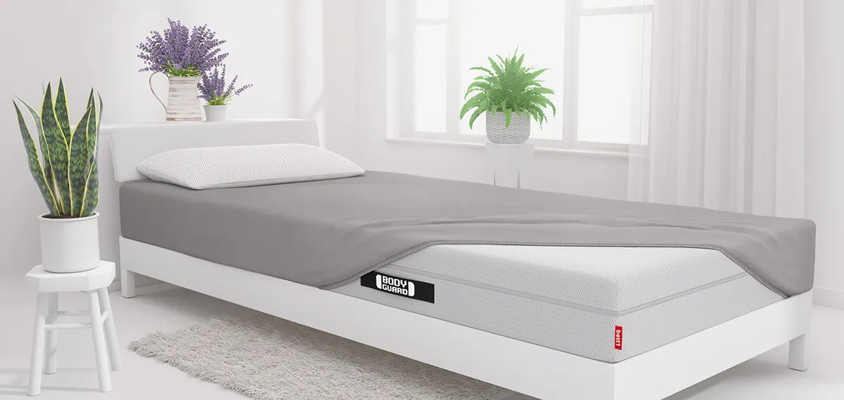 drap housse en jersey gris Bodyguard sur un matelas BODYGUARD dans une chambre
