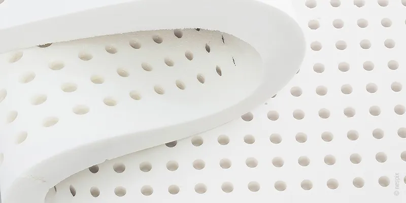 Mousse perforée blanche en gros plan, illustrant la respirabilité et la flexibilité du matériau.