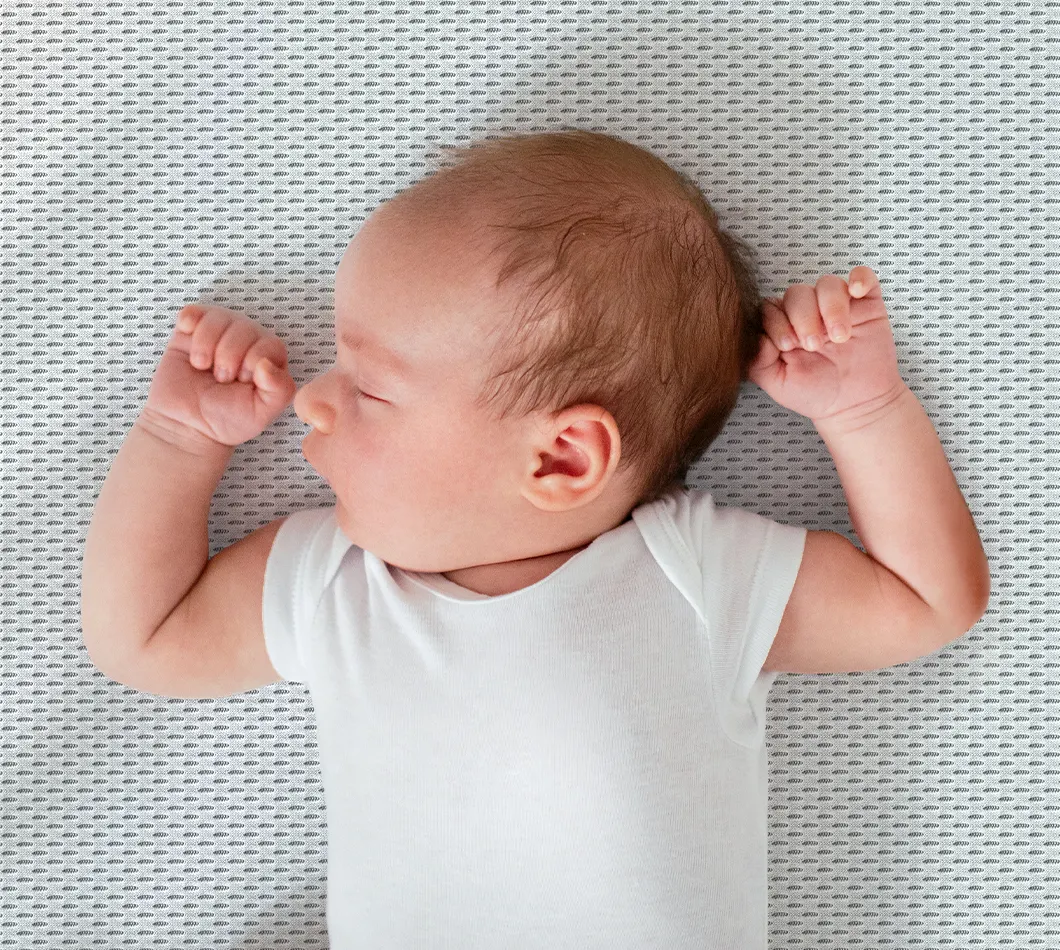 Gros plan sur un bébé debout dans un lit à barreaux sur un matelas enfant BODYGUARD