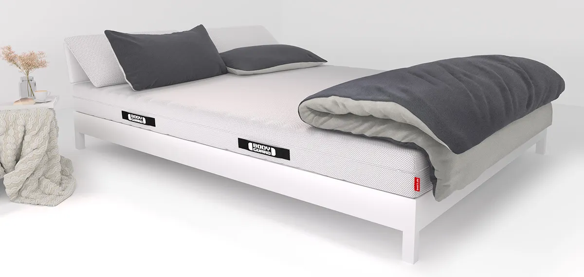Auf einem Bett liegen zwei Kissen und eine große Bettdecke