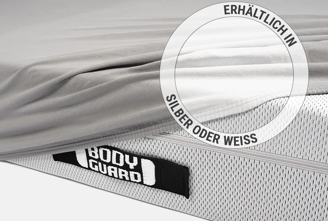 Die BODYGUARD® Matratze zur Hälfte mit dem Jersey-Spannbettlaken in Silber bezogen. Zoom auf das Laken in der weißen Farbvariante. Text: Erhältlich in Silber oder Weiß