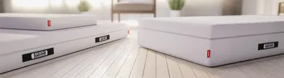 Trois matelas BODYGUARD® posés au sol dans une chambre lumineuse, montrant différentes hauteurs.