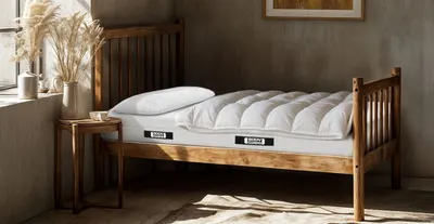 Ein rustikal anmutendes Zimmer mit einem kurzen Holzbett. Darauf liegt die BODYGUARD Anti-Kartell-Matratze 80x190 cm mit Decke und Kissen.